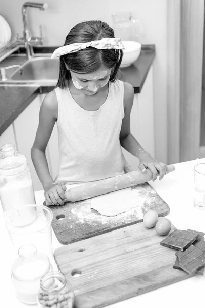 Ritratto in bianco e nero della bambina che rotola pasta cruda — Foto Stock