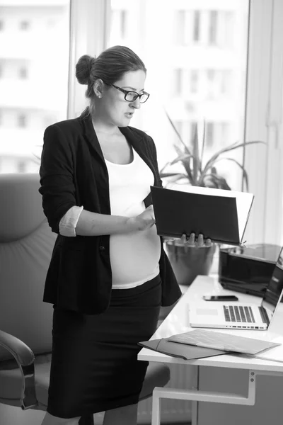 Черно-белый портрет бизнесвумен, ожидающей ребенка в офисе — стоковое фото