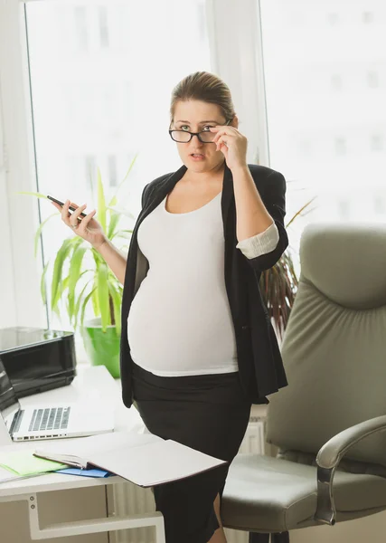 Pregnant businesswoman in black suit using mobile phone — Stock Photo, Image