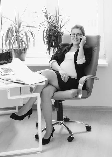 Foto en blanco y negro de una joven mujer de negocios embarazada en su varita — Foto de Stock