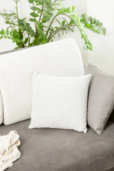 Closeup of white decorative cushion lying on gray sofa at living — Stock Photo, Image