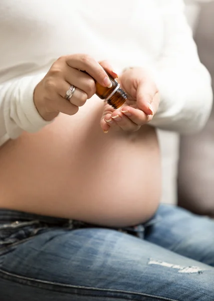 Close-up van zwangere vrouw innemen van vitamines in pillen van glas bo — Stockfoto