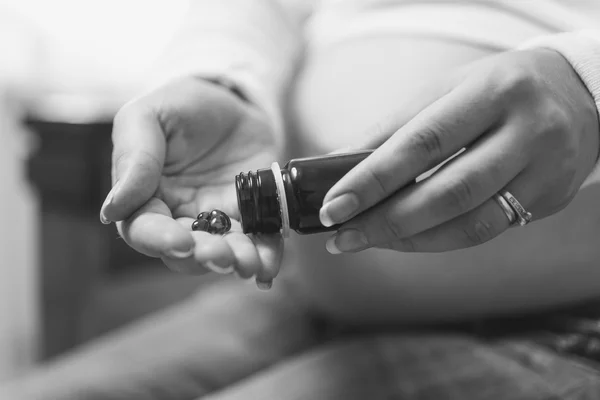 Czarno-białe zdjęcie kobiety w ciąży gospodarstwa pigułki z strony — Zdjęcie stockowe