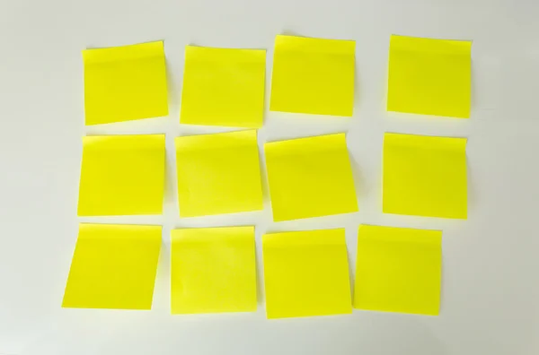 Closeup de 12 notas pegajosas amarelas em branco no quadro branco — Fotografia de Stock