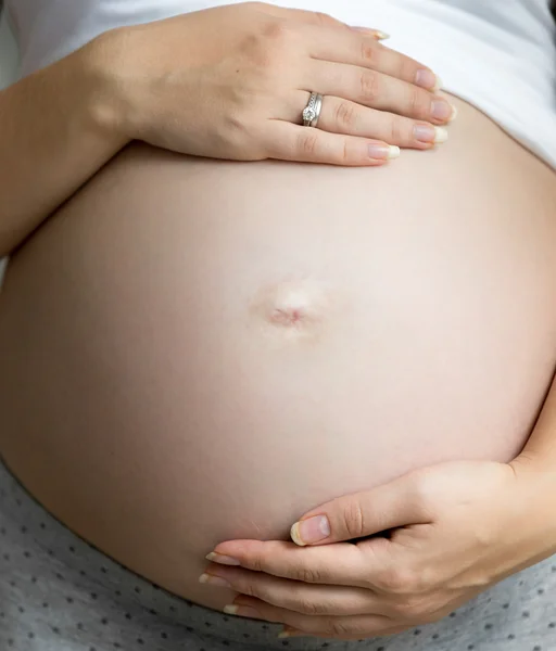 Primo piano della donna incinta che si tiene per mano sulla pancia grande — Foto Stock