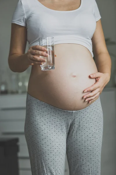 Tonas skott av gravid kvinna med glas vatten — Stockfoto