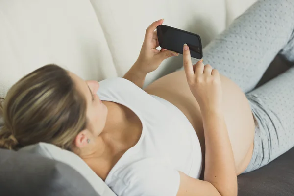 Foto di primo piano della donna incinta sdraiata sul divano e messaggio di digitazione — Foto Stock