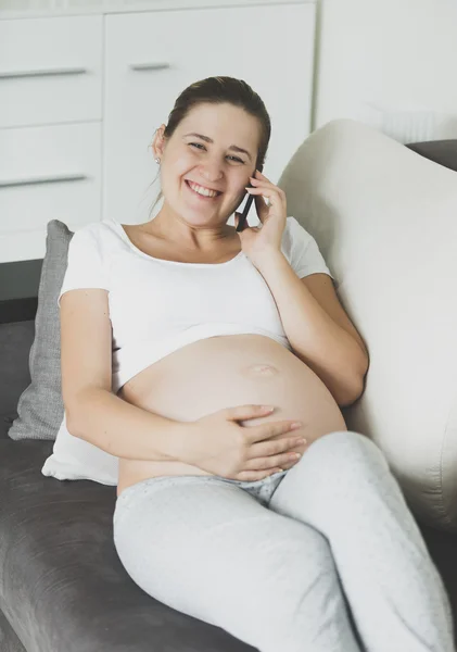 Portrait of happy pregnant woman relaxing on sofa and talking by — Stock Photo, Image