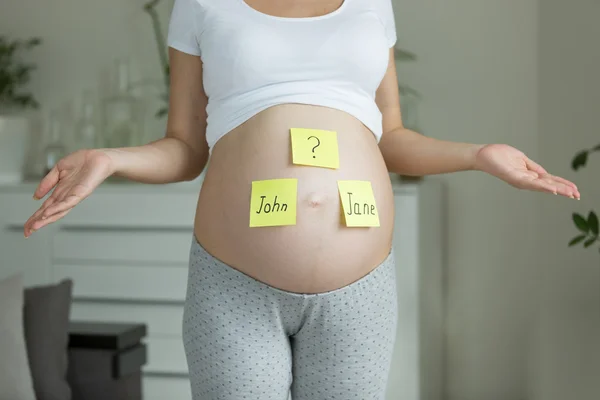 Концепция выбора имени ребенка. Беременная женщина с именами — стоковое фото