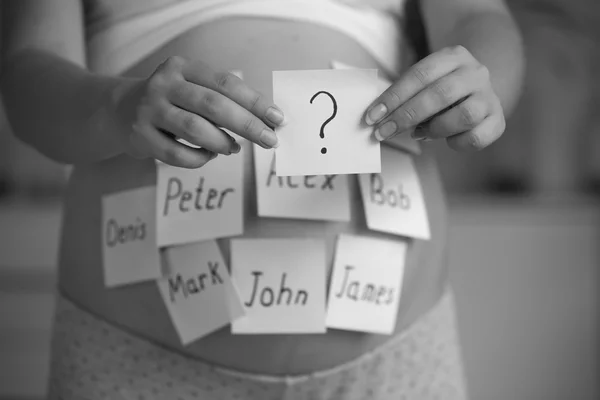 Black and white shot of pregnant woman choosing name for baby — Stock Photo, Image