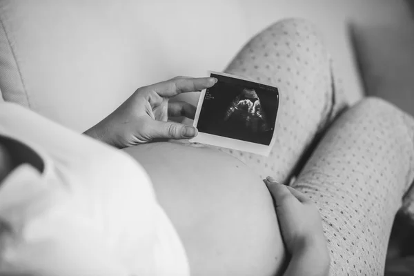 Black and white photo of pregnant woman holding ultrasound scan — Stock Photo, Image