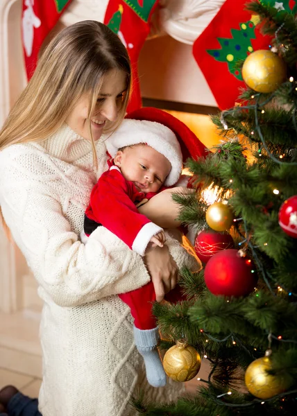 Mãe e filho recém-nascido decorando árvore de Natal com bugigangas — Fotografia de Stock