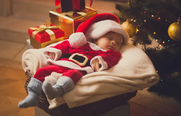 Foto tonica del neonato vestito in costume da Babbo Natale sdraiato con — Foto Stock