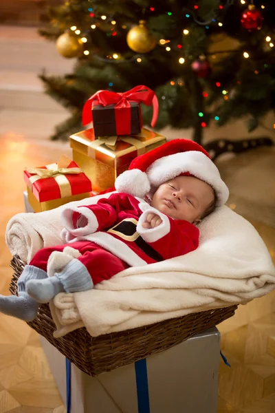 Menino em Santa fantasia dormindo sob a árvore de Natal — Fotografia de Stock