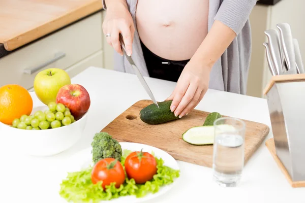 Primer plano de la mujer embarazada haciendo ensalada de verduras Imagen de archivo