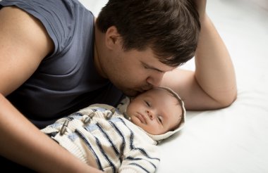 yakışıklı baba erkek yatakta yatarken bebek öpüşme