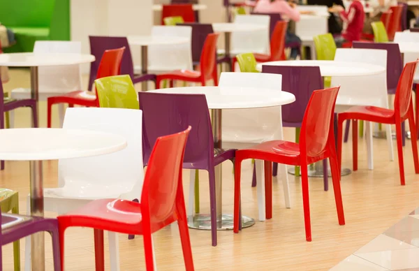 Красочные пластиковые стулья и столы в столовой — стоковое фото