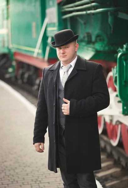 Porträtt av stilig man i kostym och bowler hat väntar trai — Stockfoto