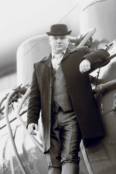 Black and white portrait of man in bowler hat standing on locomo — Stock Photo, Image