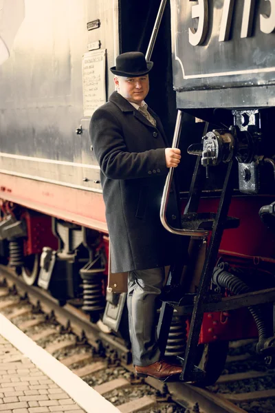 Foto tonificada del hombre en traje retro y sombrero de jugador de bolos subiendo al tren — Foto de Stock