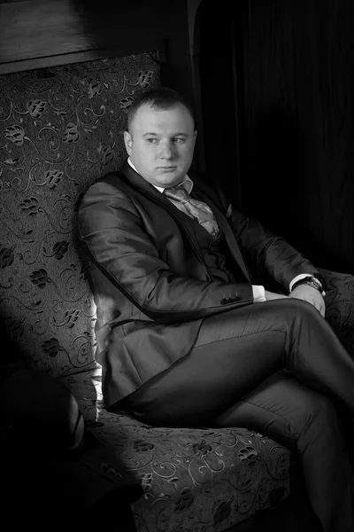 Monochrome portrait of man in retro suit sitting in train coupe — Stock Photo, Image