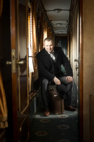 Tonificado tiro de hombre en traje vintage posando en tren — Foto de Stock