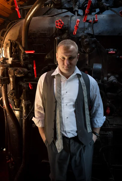 Впевнений чоловік в ретро костюмі позує в локомотивній вугільній печі — стокове фото