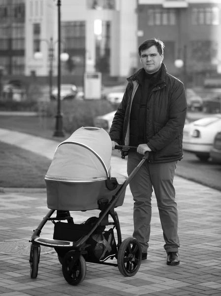 Black and white photo of happy father walking with baby in pram — Stock Photo, Image