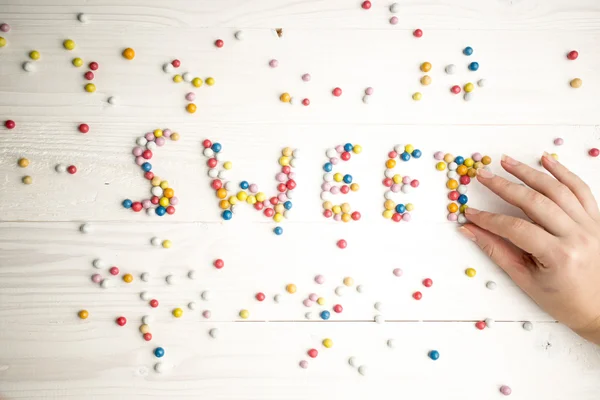 Closeup of woman making word Sweet from colorful candies — Stock Photo, Image