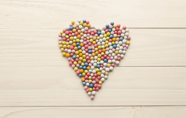 Gambar berdada dari permen bundar berwarna-warni terletak dalam bentuk hati di — Stok Foto