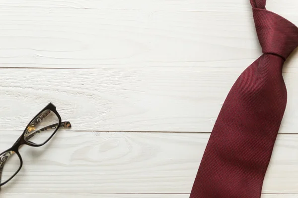 Imagem dentada de gravata e óculos deitados nas costas de madeira branca — Fotografia de Stock