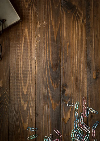 Деревянный фон с блокнотом и красочными скрепками — стоковое фото