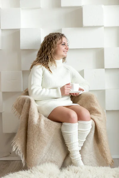 Kadın sandalyede oturan ve çay holding beyaz kazaklı — Stok fotoğraf