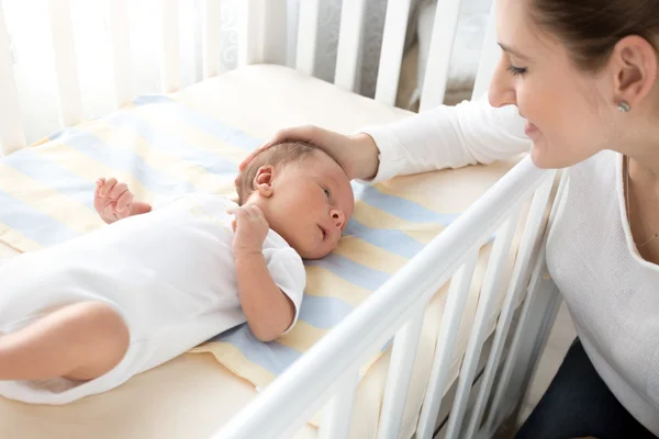 Happy smiling mother caressing her baby lying in cot — Stock Photo, Image