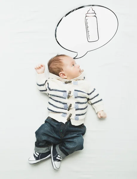 Милий хлопчик лежить на ліжку і мріє про пляшку з молоком — стокове фото