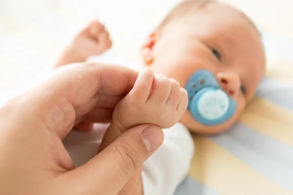 Tonade bilden av nyfött barn hålla fäder hand. Foto med sof — Stockfoto