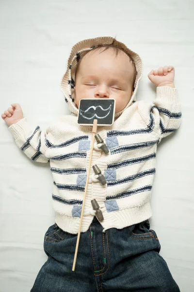 Niño con bigotes decorativos acostado en la cama — Foto de Stock