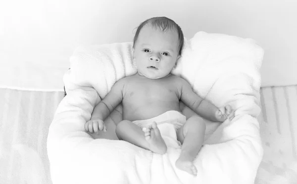 Monochromes Foto eines kleinen Babys, das auf einem großen Kissen liegt — Stockfoto