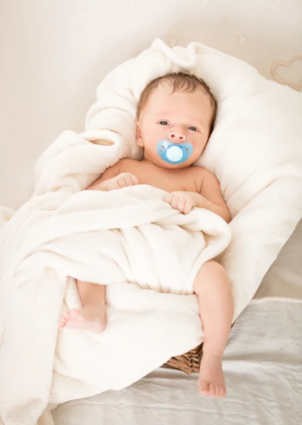 Bébé mignon avec une sucette couchée dans un panier en osier — Photo