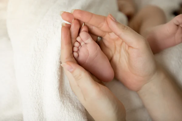 Tonas skott av nyfött barn fötter i mödrar händer — Stockfoto