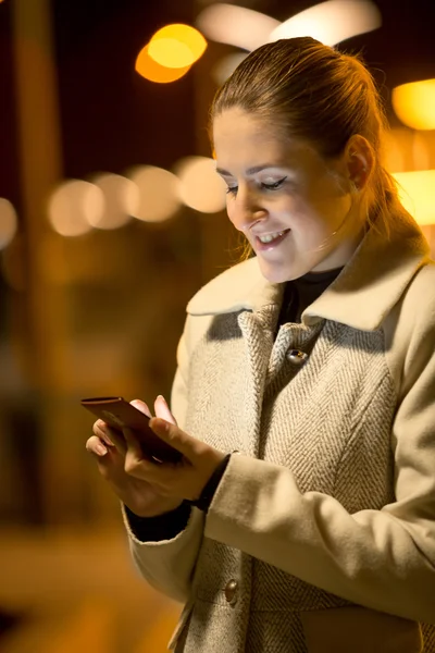 Nachtporträt einer glücklichen Frau, die SMS auf der Straße liest — Stockfoto