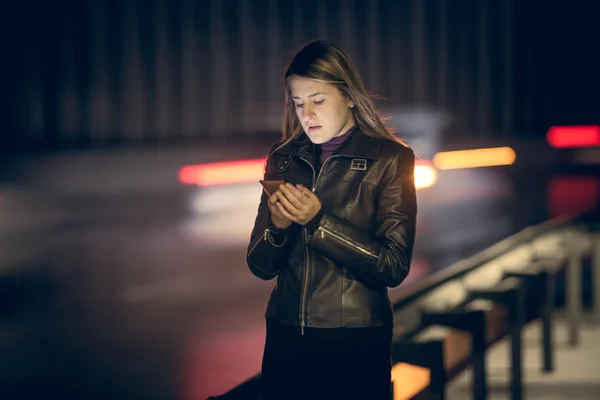 Portrait of woman with smartphone at night highway — Stock Photo, Image