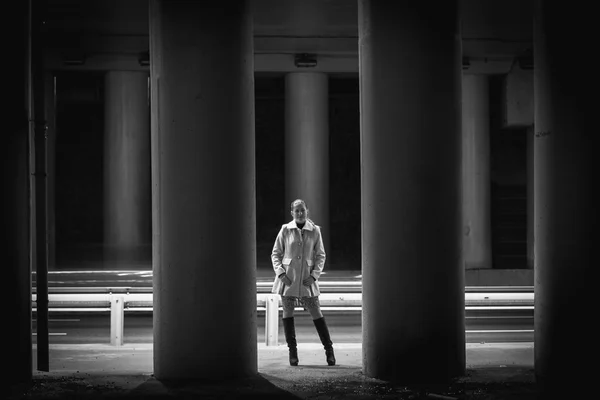 Sexy young woman posing between high columns under bridge — Stock Photo, Image