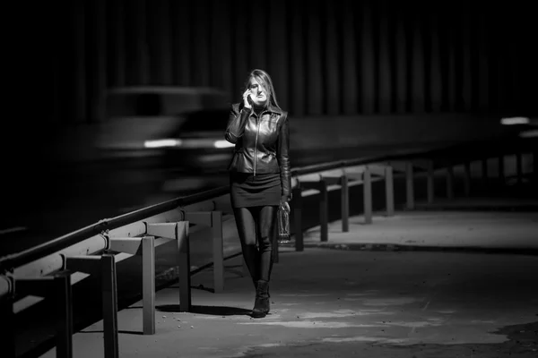 Black and white photo of lwoman walking at highway at night — Stock Photo, Image