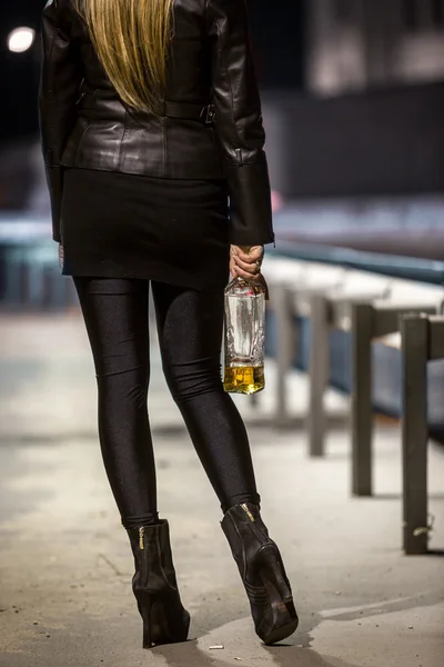 Rear view of sexy woman posing on street with whiskey — Stock Photo, Image