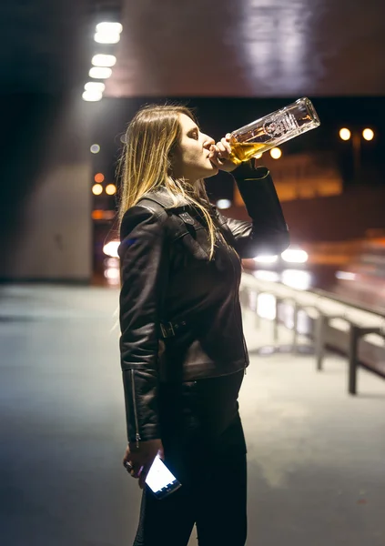 Lonely woman drinking alcohol from bottle at highway — Stock Photo, Image