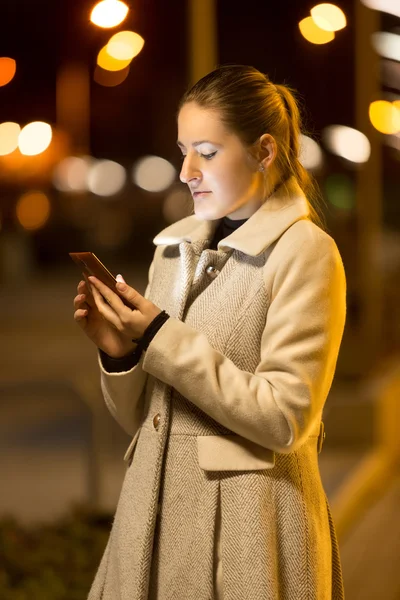 Elegant woman typing text message on street at night — Stock Photo, Image