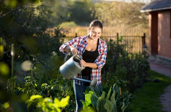 家庭菜園で植物に水をまくブルネットの女性 — ストック写真