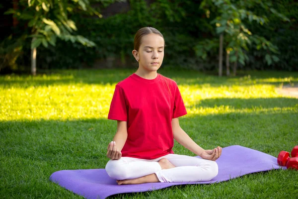 Adolescente practicando yoga sobre hierba en el parque — Foto de Stock