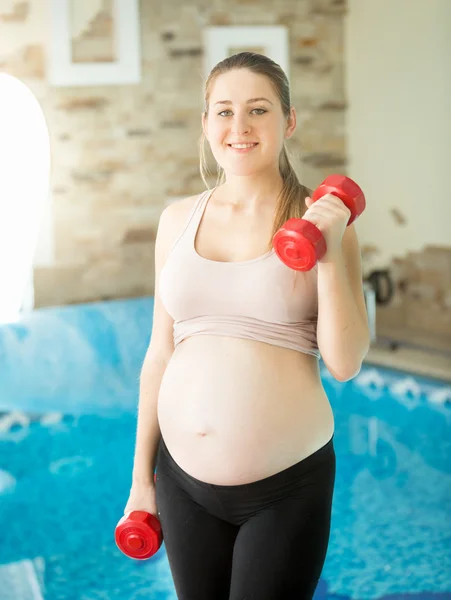 Wanita tersenyum mengharapkan bayi melakukan latihan dengan dumbbells — Stok Foto